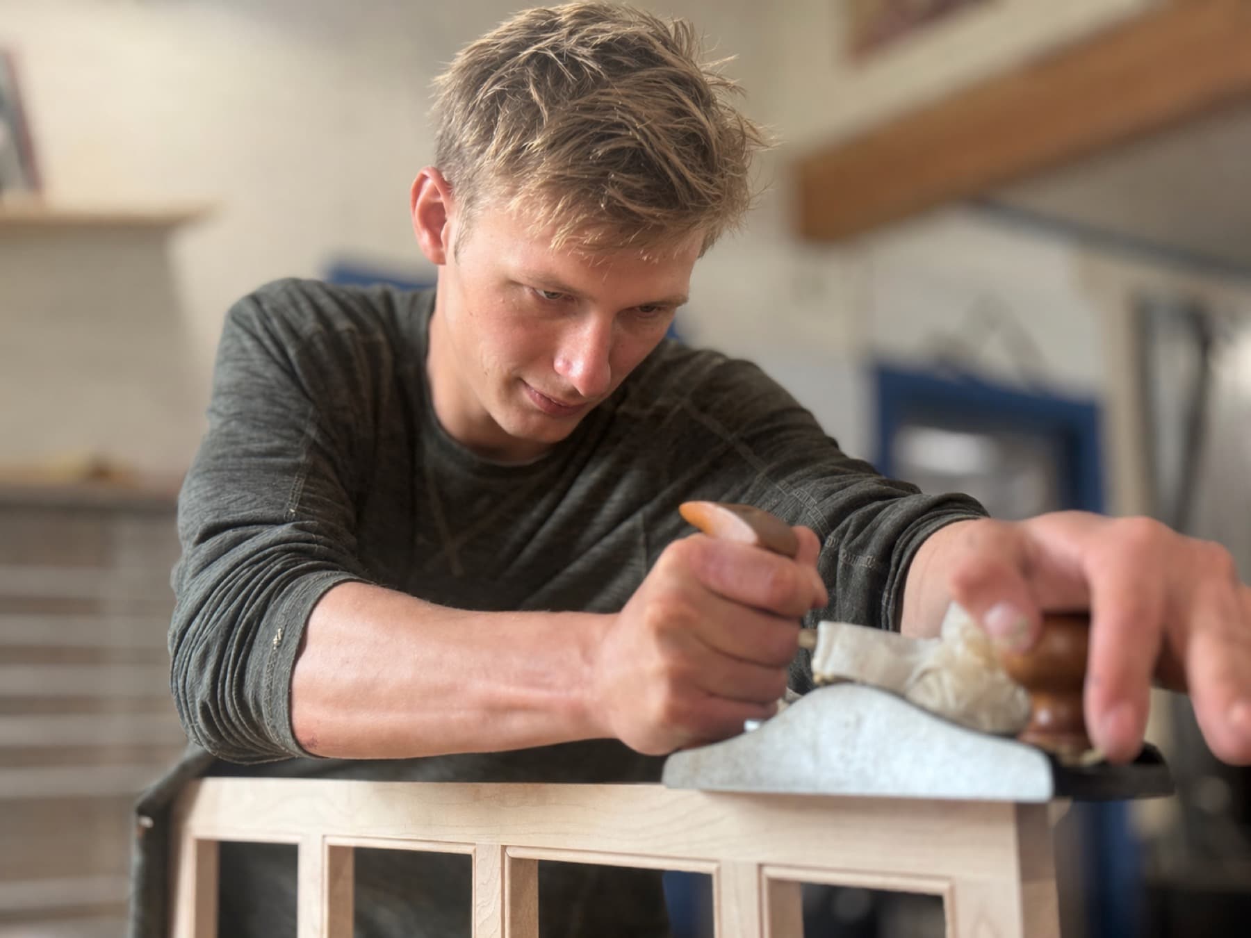 Aidan Gilbert hand planing a cabinet part in the shop